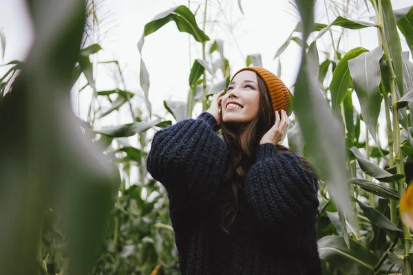 Krásné bezstarostné dlouhé vlasy asijské dívky ve žlutém klobouku a pleteném svetru v podzimní kukuřičné oblasti. Koncepce citlivosti k přírodě — Stock fotografie