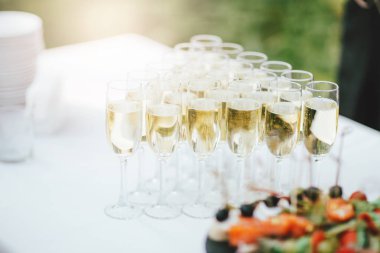 Açık havada düzenlenen etkinlikte masada şampanya ve atıştırmalıklar kadehleri, catering