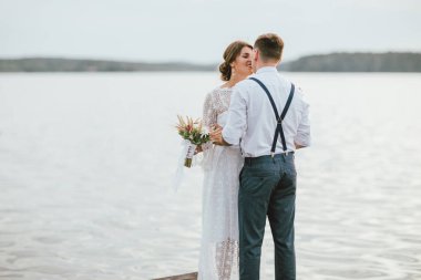 Göl yakınında Mutlu yeni evli çift, boho buketi ile gelin esmer genç kadın, açık havada