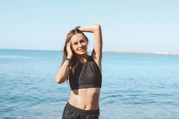 Joven delgado atlético pelo largo sonriente mujer en ropa deportiva en la playa de mar, estilo de vida saludable — Foto de Stock