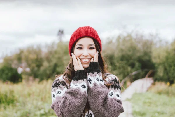 Длинные волосы, девушка в красной шапке и вязаном нордическом свитере в осеннем природном парке — стоковое фото