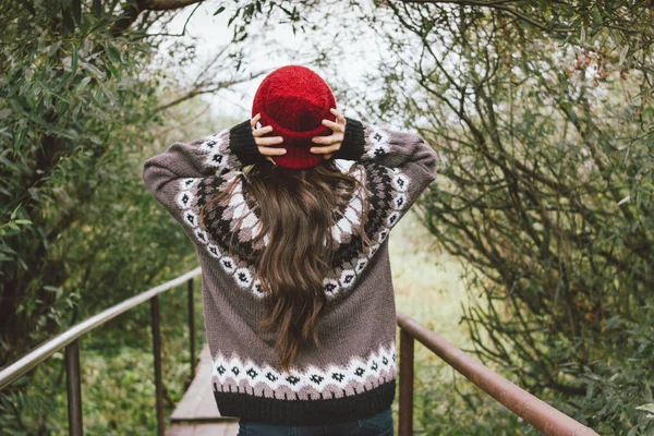 Hermoso pelo largo despreocupado chica asiática en el sombrero rojo y jersey nórdico de punto por detrás en el parque natural de otoño, viaje aventura estilo de vida — Foto de Stock