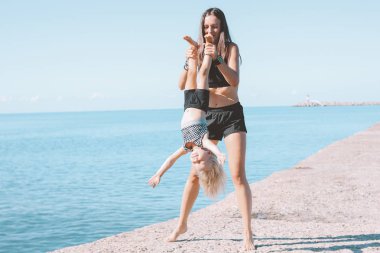 Birlikte plajda egzersiz küçük sevimli kız ile genç uygun kadın anne, sağlıklı yaşam tarzı, dinamik jimnastik