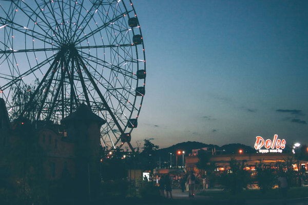 Sochi, Russia - August, 07, 2019. Glowing lights on Ferris wheel, resort nightlife, background, beautiful sky 
