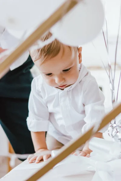 Симпатичный мальчик в белой рубашке на большой подарочной коробке с руками fother в ярком интерьере, крупным планом портрет — стоковое фото