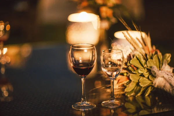 Two glasses of wine on table on the background of wedding bouquet, evening, the end of event — Stock Photo, Image