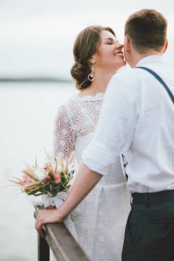 Mutlu yeni evli çift, damat ile boho tarzı buket ile gülümseyen gelin esmer genç kadın, açık havada