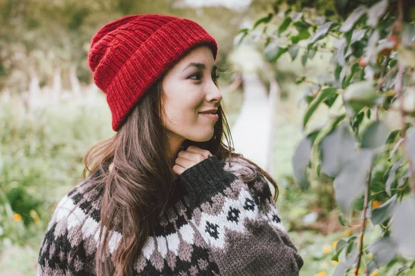 Длинные волосы, девушка в красной шапке и вязаном нордическом свитере в осеннем природном парке — стоковое фото