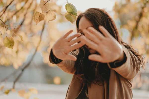 Mulher morena com cabelos longos encaracolados no casaco puxando as mãos para a câmera, temporada de outono — Fotografia de Stock