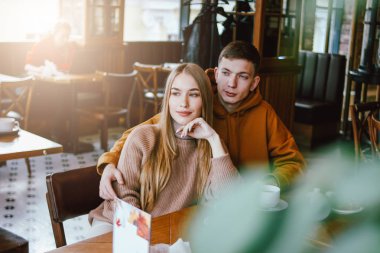 Genç çift birlikte kafede oturan sıcak rahat giyim giyinmiş