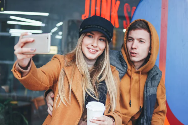 Счастливая молодая пара влюбленных подростков друзья одеты в случайный стиль делая селфи на улице города в холодное время года — стоковое фото