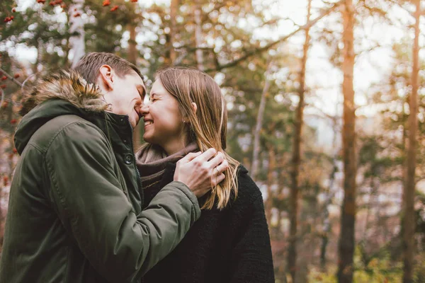 Ευτυχισμένο νεαρό ζευγάρι ερωτευμένων φίλων ντυμένοι με περιστασιακό στυλ φιλιά στο δάσος του πάρκου της φύσης σε ψυχρή εποχή, οικογενειακά ταξίδια περιπέτειας — Φωτογραφία Αρχείου