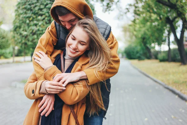 Felice giovane coppia innamorata adolescenti amici vestiti in stile casual seduti insieme sulla strada della città di autunno — Foto Stock