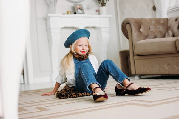 Cute fashion trendy fair hair little girl dressed in denim overalls, leopard scarf and blue beret with mom's accessories. Daughter imitates mom — Stock Photo, Image