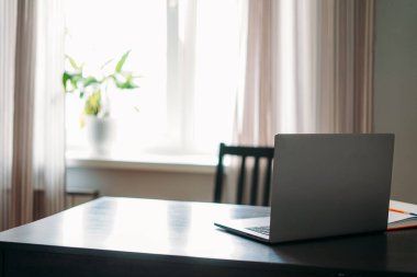 Siyah masada cep telefonu ve pencereye karşı notlarla açılan dizüstü bilgisayar.