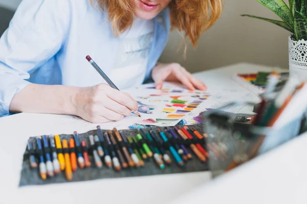 Crop photo of young woman with red hair illustrator artist draws at desk at home office