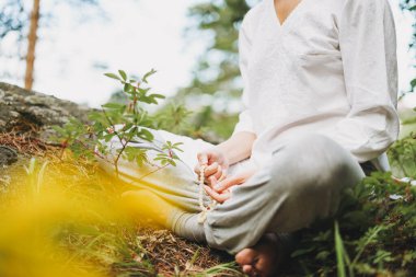 Boncuklu genç bir kadın ormanda yoga yapıyor. Yeni normal sosyal mesafe. Fiziksel ve zihinsel sağlık