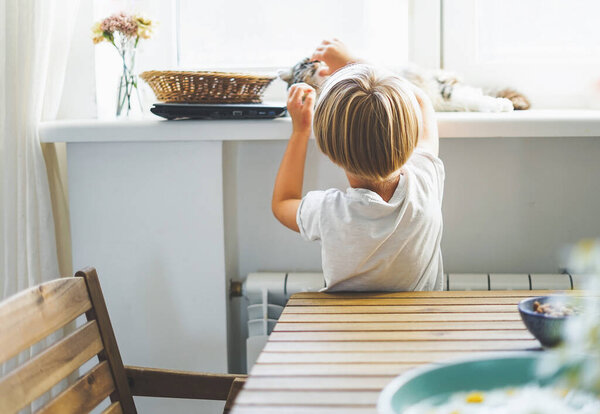 Симпатичный блондин в белой футболке с котом в светлой комнате дома