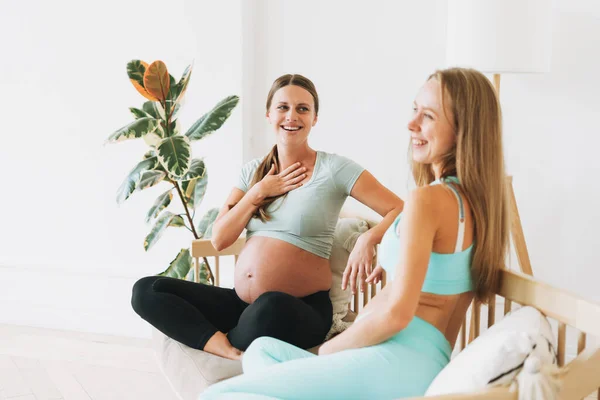 Spor Üniformalı Iki Hamile Kadın Kanepenin Üzerinde Oturmuş Gülüyorlar — Stok fotoğraf