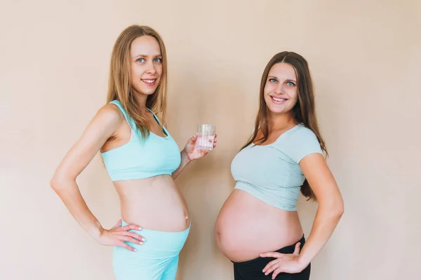 Jonge Zwangere Vrouwen Sport Met Een Glas Water Geïsoleerd Beige — Stockfoto
