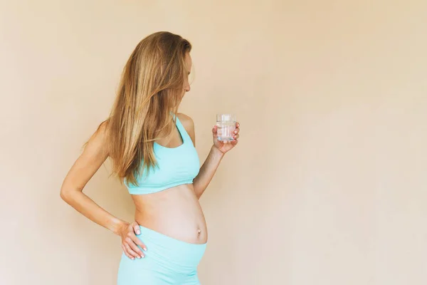 Jonge Zwangere Vrouw Mint Sportkleding Met Glas Water Geïsoleerd Beige — Stockfoto