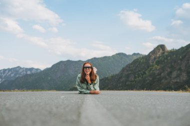 Yoldaki günlük kıyafetlerle, dağlara seyahat ederek, Altai 'de güzel, gülümseyen genç kadın gezgin.
