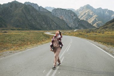 Yoldaki kaykaylı genç kadın güzel dağ manzarasına karşı, Chemalskiy Yolu, Altai