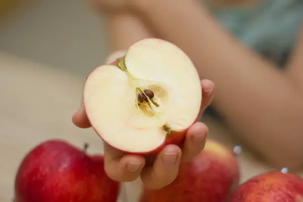 woman gives half of fresh juicy apple.