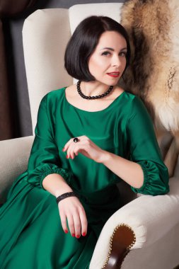 Vintage bir sandalyede oturuyor poz ipek yeşil giysili güzel esmer kadın. Bohem tarzı.