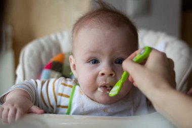 İlk bebek kaşık gelen besleme. Anne beslemeleri bebek homojenize kıyılmış gıda bir kaşıkla. Çocuk Bakımı