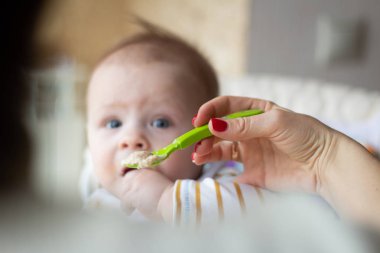 İlk bebek kaşık gelen besleme. Anne beslemeleri bebek homojenize kıyılmış gıda bir kaşıkla. Çocuk Bakımı