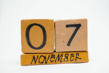 7 Kasım. Gün 7 ay, beyaz arka plan üzerinde izole el yapımı ahşap takvim. Sonbahar ay, gün yıl kavramın.