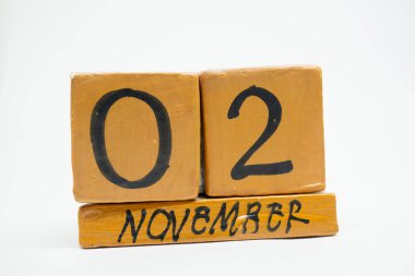 2 Kasım. Gün 2 ay, beyaz arka plan üzerinde izole el yapımı ahşap takvim. Sonbahar ay, gün yıl kavramın.