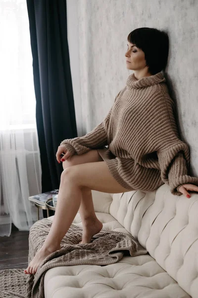 ベッドでポーズ暖かいニットのセーターの豪華な若いブルネットの女性 — ストック写真