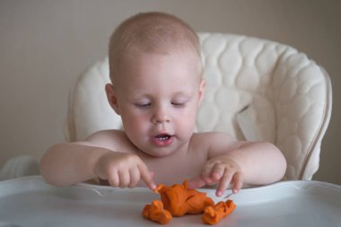 Çocukların yaratıcılığı. Bebek kilden heykel yapmaya çalışıyor. Masada plasticine sevimli küçük çocuk kalıp