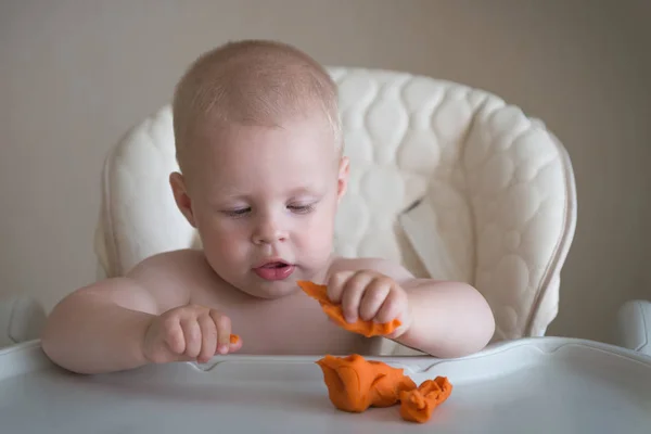 Criatividade infantil. o bebê está tentando esculpir de barro. Molde menino bonito de plasticina na mesa — Fotografia de Stock