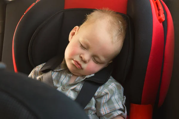 Enfant garçon dort paisiblement et en sécurité tout en étant fixé avec les ceintures de sécurité dans la voiture. — Photo