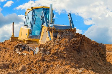 Crawler buldozer - mavi gökyüzü ve bulutlar ile bir arka plan üzerinde kırpma yolu ile ekskavatör. şantiye veya kum çukurunda çalışma