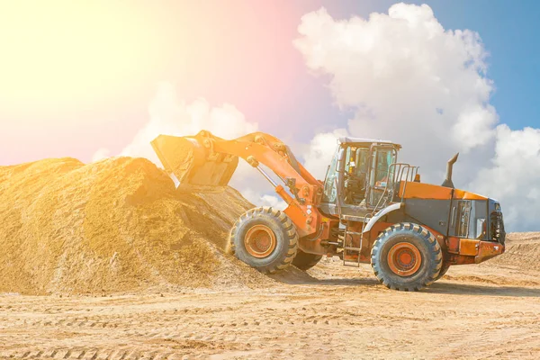 Yellow excavator on a construction site against blue sky. wheel loader at sandpit during earthmoving works — Stock Photo, Image