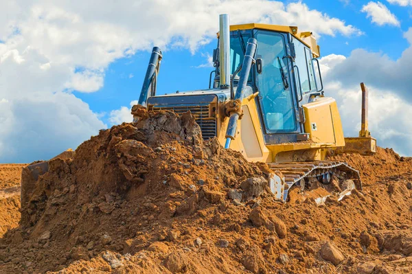 Rolovač buldozer-rýč s ořezovou cestou na pozadí s modrou oblohou a mraky. práce na staveništi nebo v písečné jámě — Stock fotografie