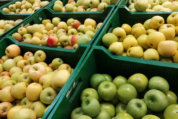 Las manzanas orgánicas en cajas de plástico en el supermercado se clasifican por variedades. manzanas frescas almacenar el fondo. Frutas en las paletas en la tienda ecológica Imagen De Stock