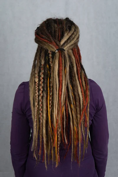 Woman with long dreadlocks shot from behind. Rear view of hairstyle dreadlocks. dreadlocks on the head of a young girl. Girl with the African pigtails. — Stock Photo, Image