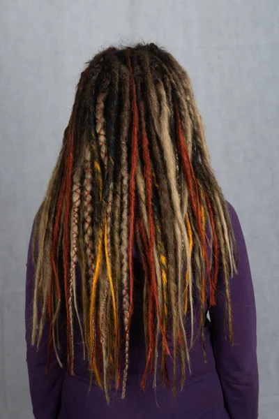 Woman with long dreadlocks shot from behind. Rear view of hairstyle dreadlocks. dreadlocks on the head of a young girl. Girl with the African pigtails. — Stock Photo, Image