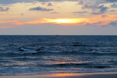 Okyanusun üzerinde güzel kırmızı gün batımı. Deniz yüzeyinin altında büyük sarı güneşli, parlak bir gün batımı. günbatımı deniz manzarası