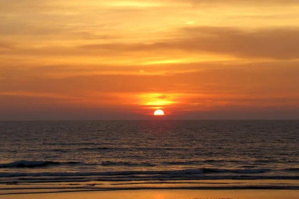 Красивый красный закат над океаном. Яркий закат с большим желтым солнцем под поверхностью моря. закатный морской пейзаж — стоковое фото