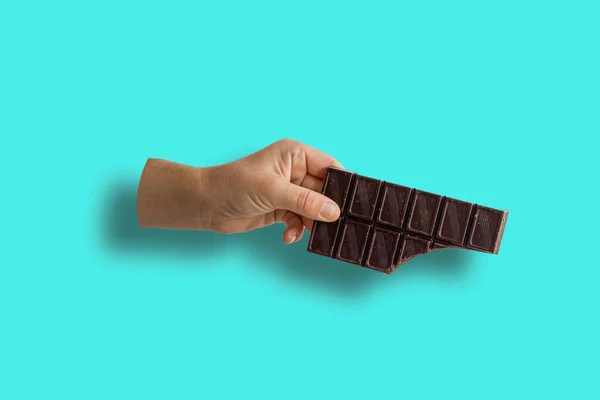 Närbild av Beskuren Hand Holding Bruten Mjölk Choklad Bar Över Blå bakgrund — Stockfoto