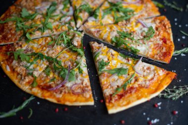 Geleneksel İtalyan pizzası. Dilimler halinde dilimlenmiş lezzetli taze pizza otlar ve peynirle koyu bir arka planda. Üst Manzara. Pizza siyah masada. Seçici odak