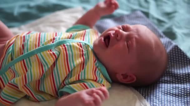 Маленька новонароджена дівчинка плаче голосно лежачи на ліжку — стокове відео