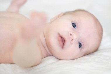 İki haftalık yeni doğmuş kız yatakta uzanıyor ve etrafa bakınıyor.