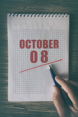 8 Ekim. Ayın 8 'inde insan elini kırmızı altı çizili not defteriyle kapat. Sonbahar ayı, yılın günü konsepti..